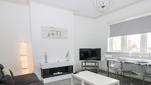 Una sala de estar moderna con un sofá, una mesa de centro, un televisor y una chimenea.