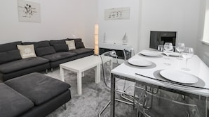 Una sala de estar moderna con un sofá, una mesa de centro y una mesa de comedor preparada para cuatro comensales.