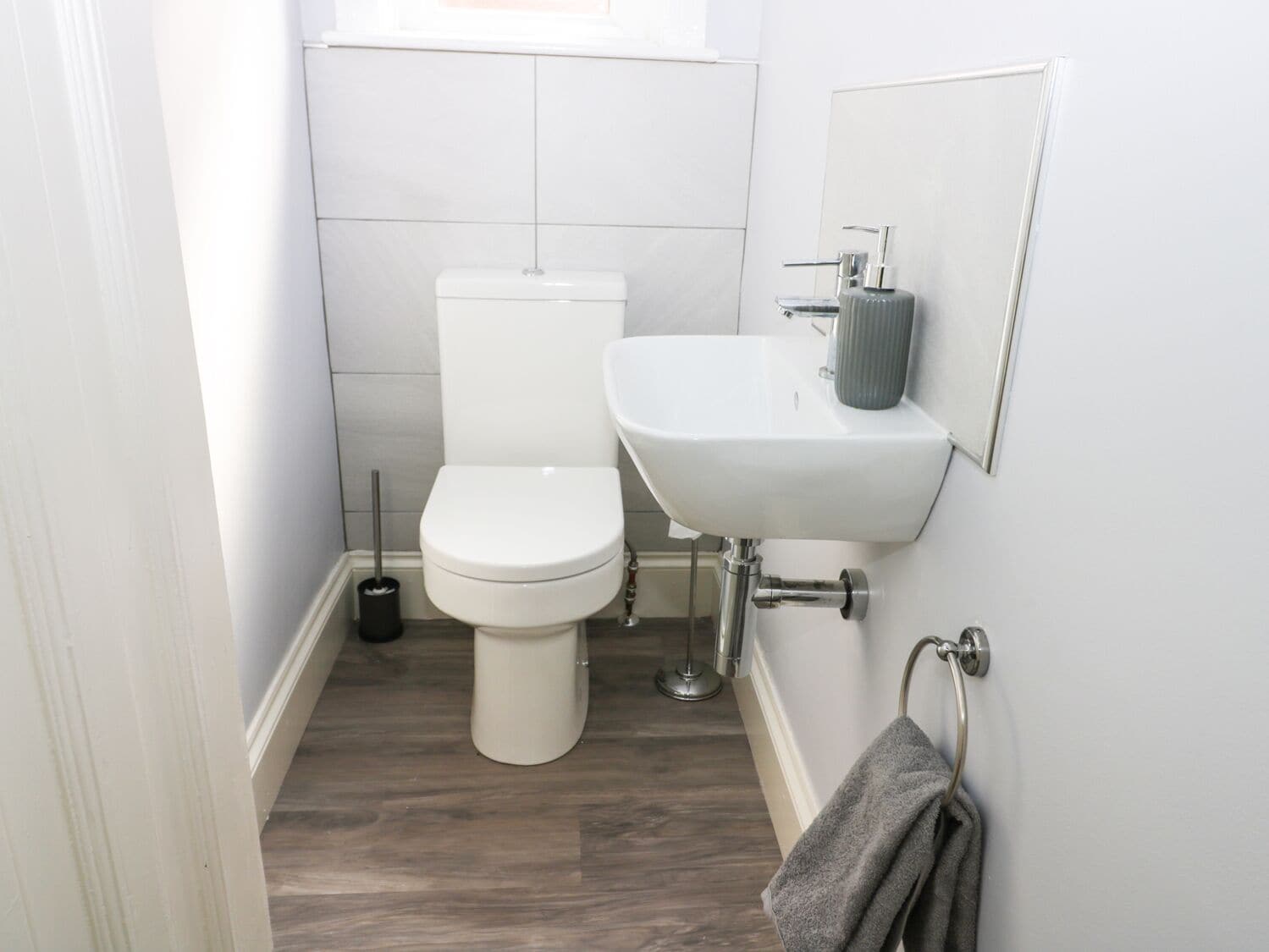 A small, clean bathroom with a toilet, sink, and a towel rack.