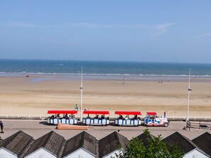 A beachside view with a row of red-roofed, blue and white beach buggies parked along the shore.