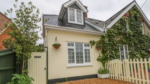 Ein Haus mit hellbeiger Fassade, einem weißen Fenster und einem weißen Zaun.