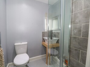 Et badeværelse med toilet, håndvask og brusekabine i glas.