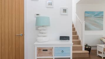 Uma escada com um quadro, um armário branco com gavetas e uma porta de madeira.