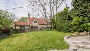 A stone house with a red-tiled roof, surrounded by a well-maintained lawn and stone walls. - Manor Cottage (Pickering)
