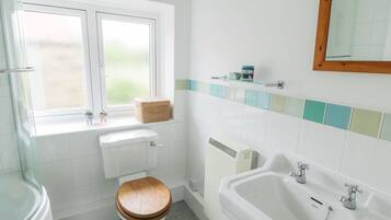 Een badkamer met toilet, raam, wastafel en spiegel.