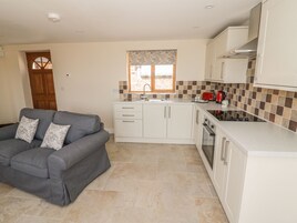 A compact kitchen with white cabinets, a red toaster, and a window with patterned curtains.