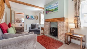 A cozy living room with a fireplace, a sofa set, and a dining area. - Moor Croft (Whitby)