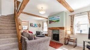 A living room with a staircase, a fireplace, and a sofa. - Moor Croft (Whitby)