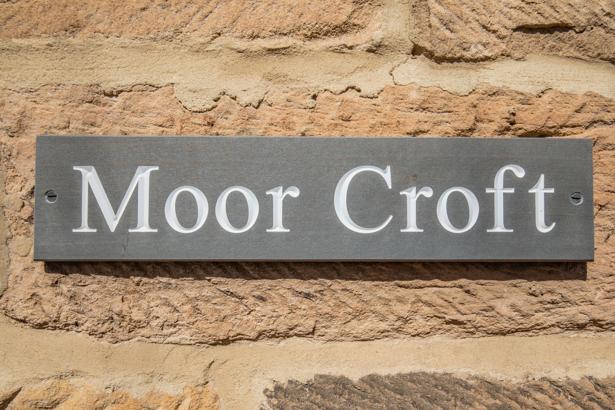 A sign with the name "Moor Croft" on a stone wall.