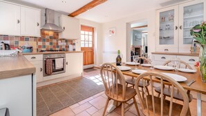 A kitchen with white cabinets, a wooden ceiling, and a dining area with a table set for four. - Moor Croft (Whitby)