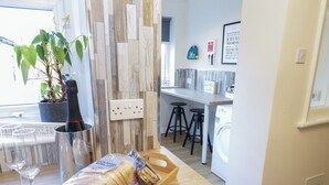 Une cuisine avec un plan de travail en bois, une plante en pot, un verre à vin et un plateau avec du pain et du lait.