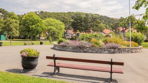 Un parc avec un banc, un drapeau et un mur de pierre orné de fleurs.