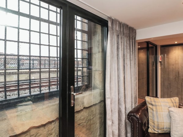 A room with a large window, a door, and a view of a train track outside. - Tornado @ Engine Shed (Whitby)