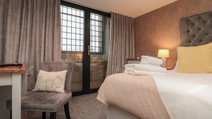 A hotel room with a bed, a chair, a desk, and a window with curtains. - Tornado @ Engine Shed (Whitby)