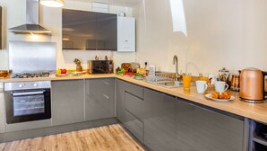 Eine moderne Küche mit Edelstahlgeräten, einer Holzarbeitsplatte und einem eingebauten Backofen.