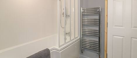 A bathroom with a shower, a towel rack, and a door.