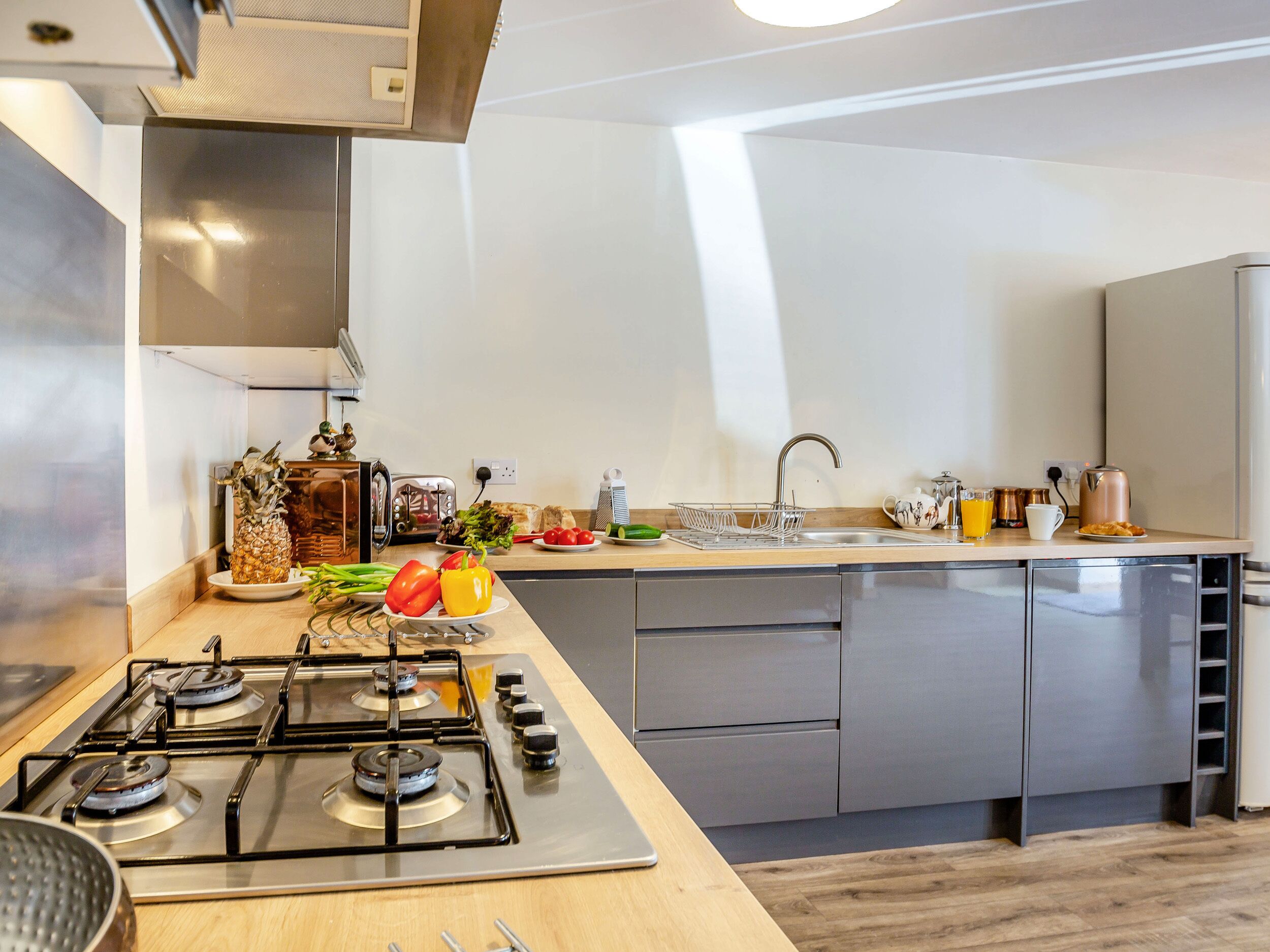 A modern kitchen with a gas stove, stainless steel appliances, and a wooden countertop.