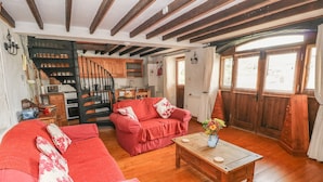 A cozy living room with a red sofa, wooden coffee table, and a staircase leading to a kitchen. - Primose Cottage (Milford Haven)