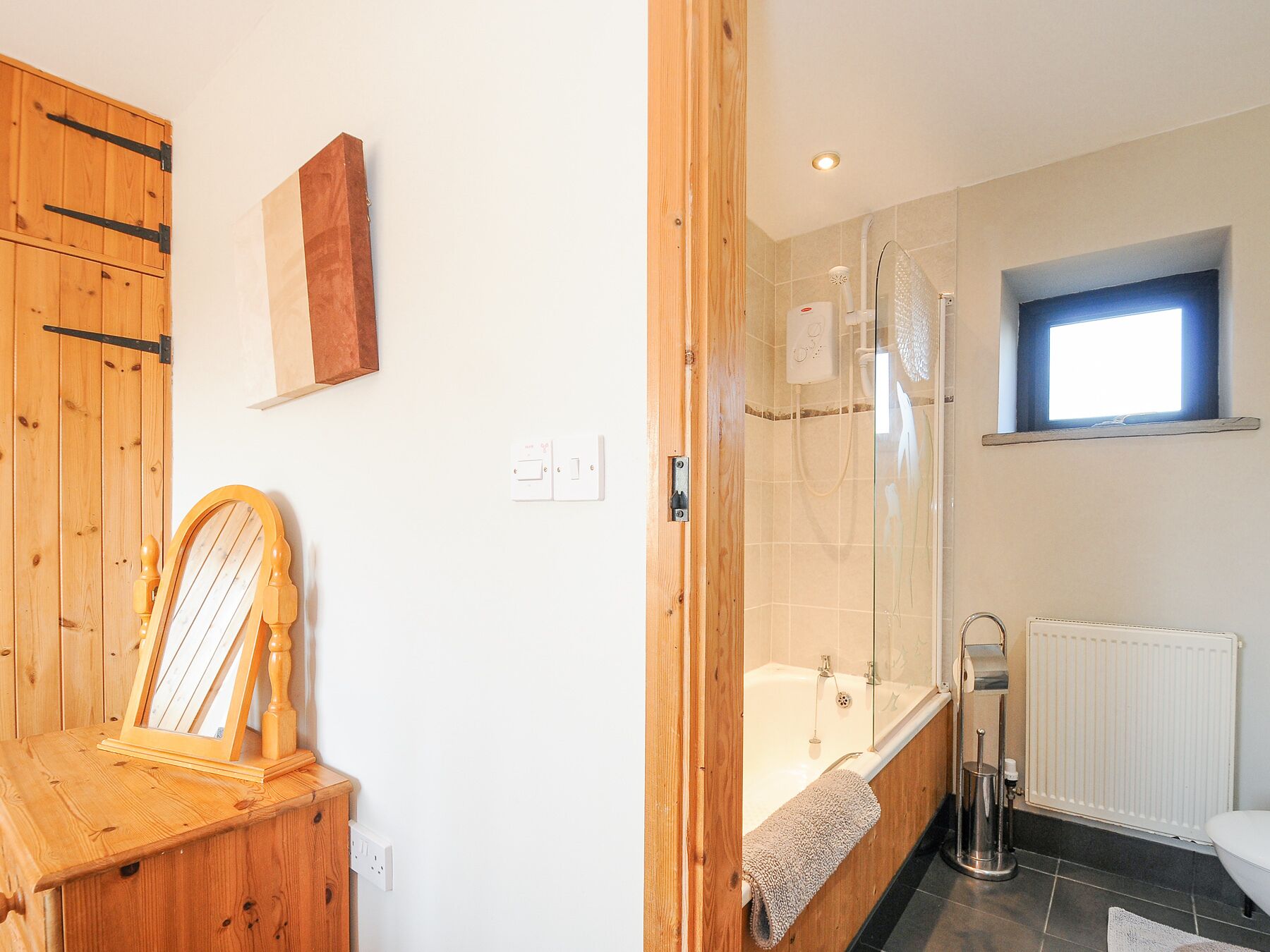 Une salle de bain avec un meuble en bois, un miroir encadré, une douche, une baignoire et une fenêtre.