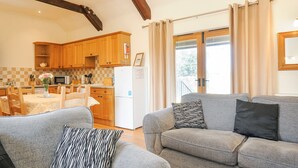 Ein gemütliches Wohnzimmer mit einer grauen Couch und einem Essbereich mit Holzschränken und einem weißen Kühlschrank.