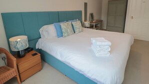 Une chambre à coucher avec un grand lit, une table de chevet, une lampe, une chaise, un bureau et une armoire.