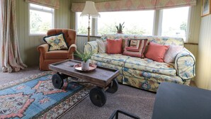 Un salón acogedor con un sillón marrón, un sofá estampado y una alfombra con diseño.