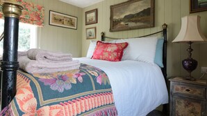 Una cama bien hecha con una colcha floral, una pila de toallas y una mesita de noche con una lámpara.