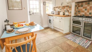 A kitchen with white cabinets, a stove, and a microwave. - Cutlers Cottage (Matlock)