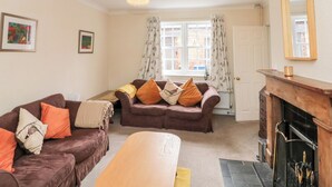 A cozy living room with two sofas, a wooden coffee table, a fireplace, and a large window with curtains. - Bella's Cottage (Driffield)