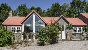 A two-story house with a red roof and a large central window. - Drumhead Bothy (Banchory)