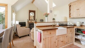 A cozy kitchen with wooden cabinets, a central island, and a fireplace. - Drumhead Bothy (Banchory)