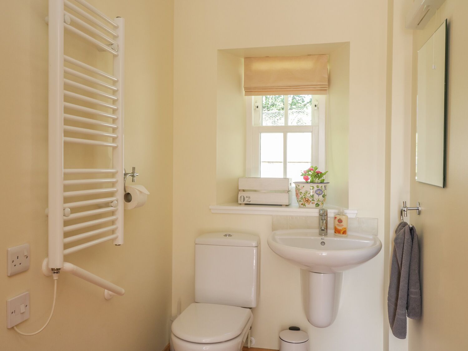 Un baño con inodoro, lavabo, toallero y ventana con vistas a la vegetación.