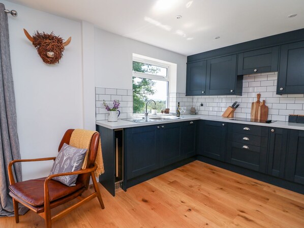 Una cocina moderna con armarios azul oscuro, encimera blanca y suelo de madera.