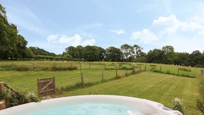 A hot tub in a grassy field with a wooden gate and a fence. - Owl Cottage (Llandrindod Wells)
