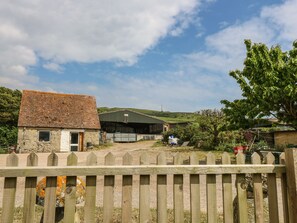 A rural property with a stone house, a metal barn, and a fenced area. - Chale Farm Lodge (Ventnor)
