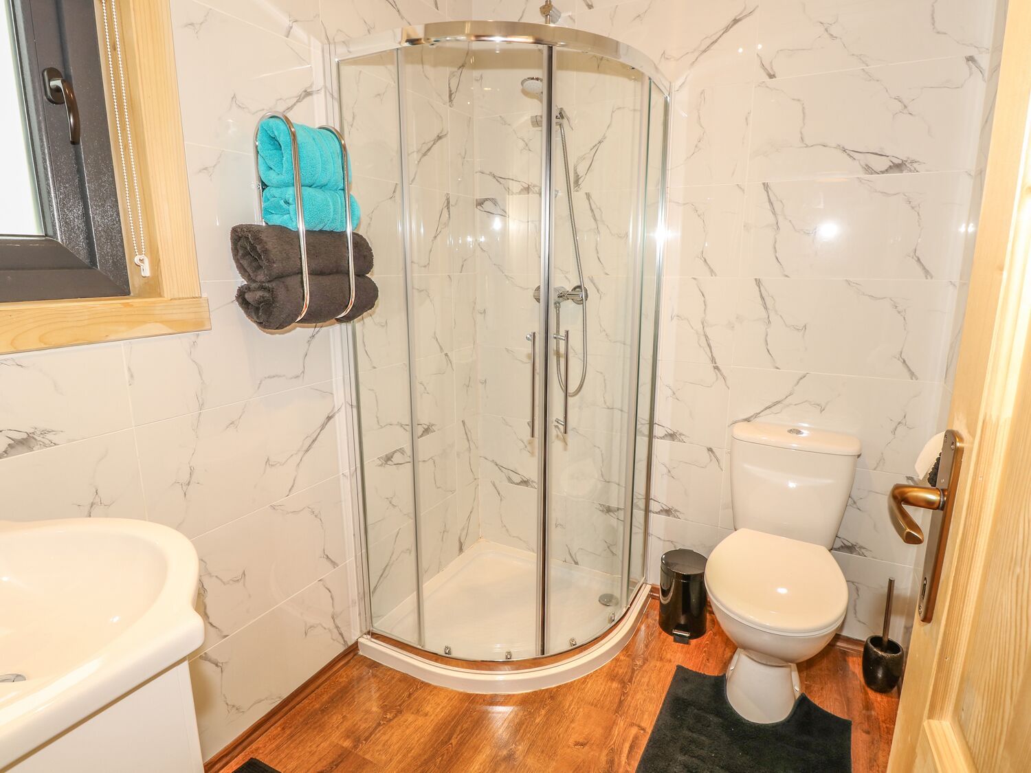 A bathroom with a glass-enclosed shower, a toilet, and a sink.