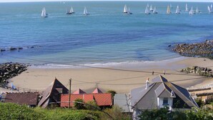 A coastal scene with sailboats on the water, a sandy beach, and houses with red roofs. - Chale Farm Lodge (Ventnor)