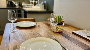 Een eettafel met twee borden, een vork, een mes en een wijnglas. Op tafel staat een potplant.