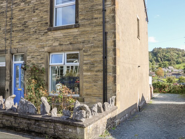 A stone building with a blue door, a window, and a stone wall with rocks.