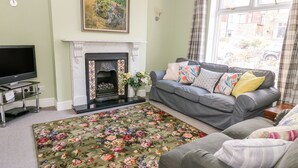 A living room with a fireplace, a sofa, a TV, and a floral rug.