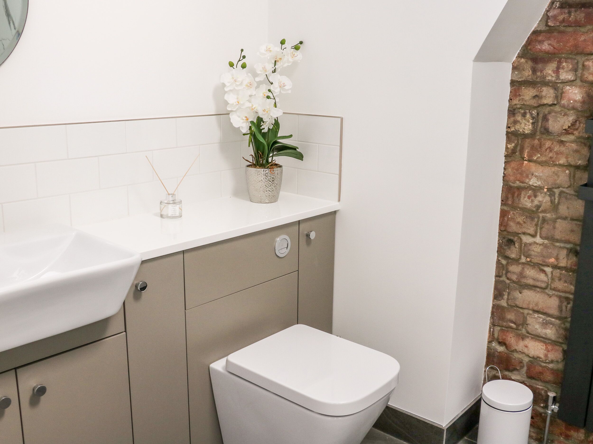 Een badkamer met een wit wastafel, toilet en een potorkidee op het aanrecht.