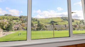 A view from a window overlooking a green field and a village with houses and a church.
