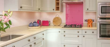 A kitchen with white cabinets, a pink backsplash, and stainless steel appliances.