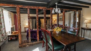 A dining room with a wooden table, chairs, and a fireplace. - Penlone Cottage (Rhayader)