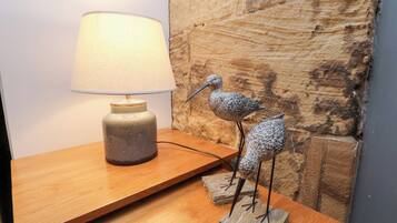 A wooden table with a lamp and two bird sculptures.