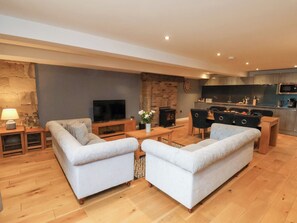 Uma sala de estar moderna com dois sofás, uma TV, uma lareira e uma área de cozinha com micro-ondas.