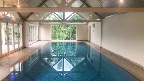 Ein Hallenbad mit freiem Blick auf die umliegende Grünfläche durch große Fenster.