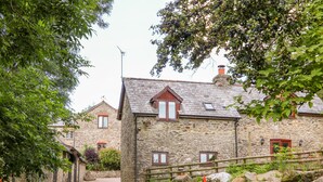 Ein Steinhaus mit einem Kiesweg, der zu einem Holztor führt.