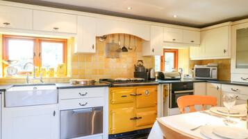A kitchen with white cabinets, a yellow stove, and a dining table set for two.