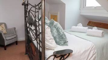Une chambre à coucher avec un lit à baldaquin, une petite table de chevet, une chaise et une fenêtre donnant sur l’extérieur.